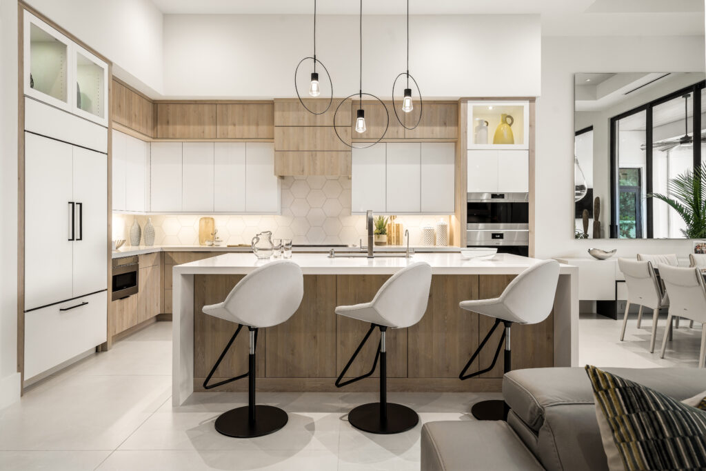 Modern kitchen interior with clean lines, a central island, pendant lighting, and white bar stools.